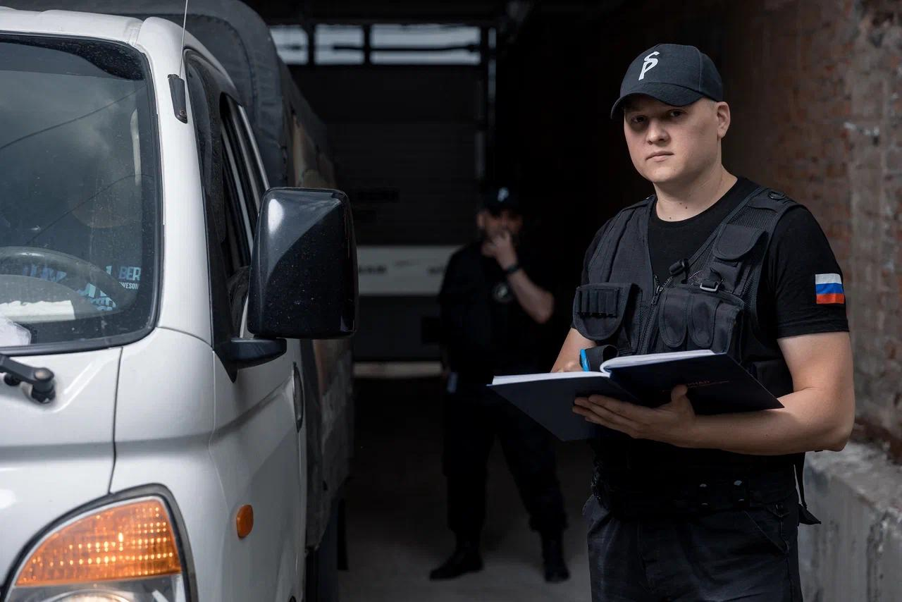 Сотрудник охраны ведёт записи у въезда на объект